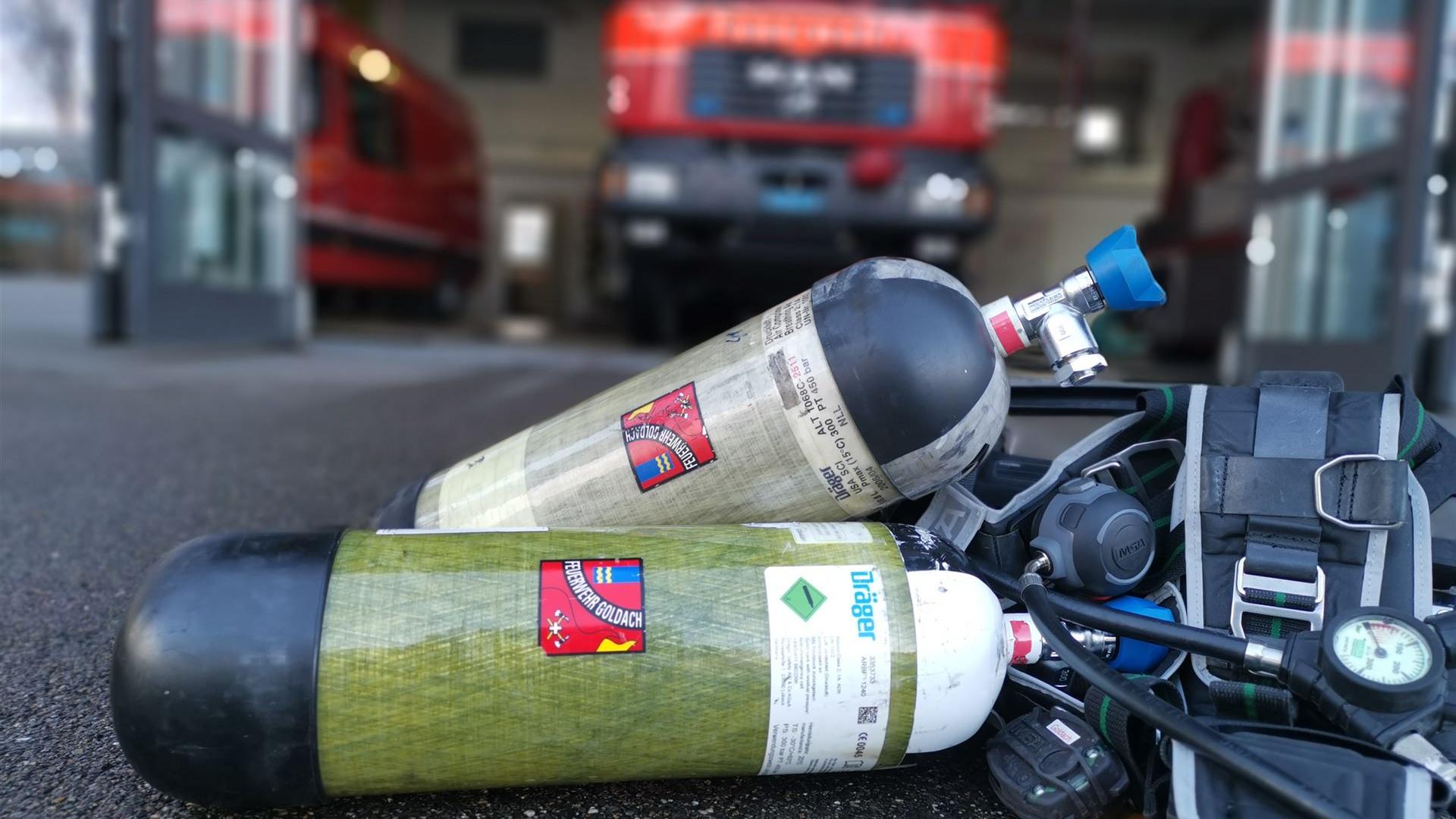 Atemschutzausrüstung der Feuerwehr Goldach im Feuerwehrdepot Atemschutzgeräte der Feuerwehr Goldach vor einem geöffneten Feuerwehrdepot mit Einsatzfahrzeug im Hintergrund